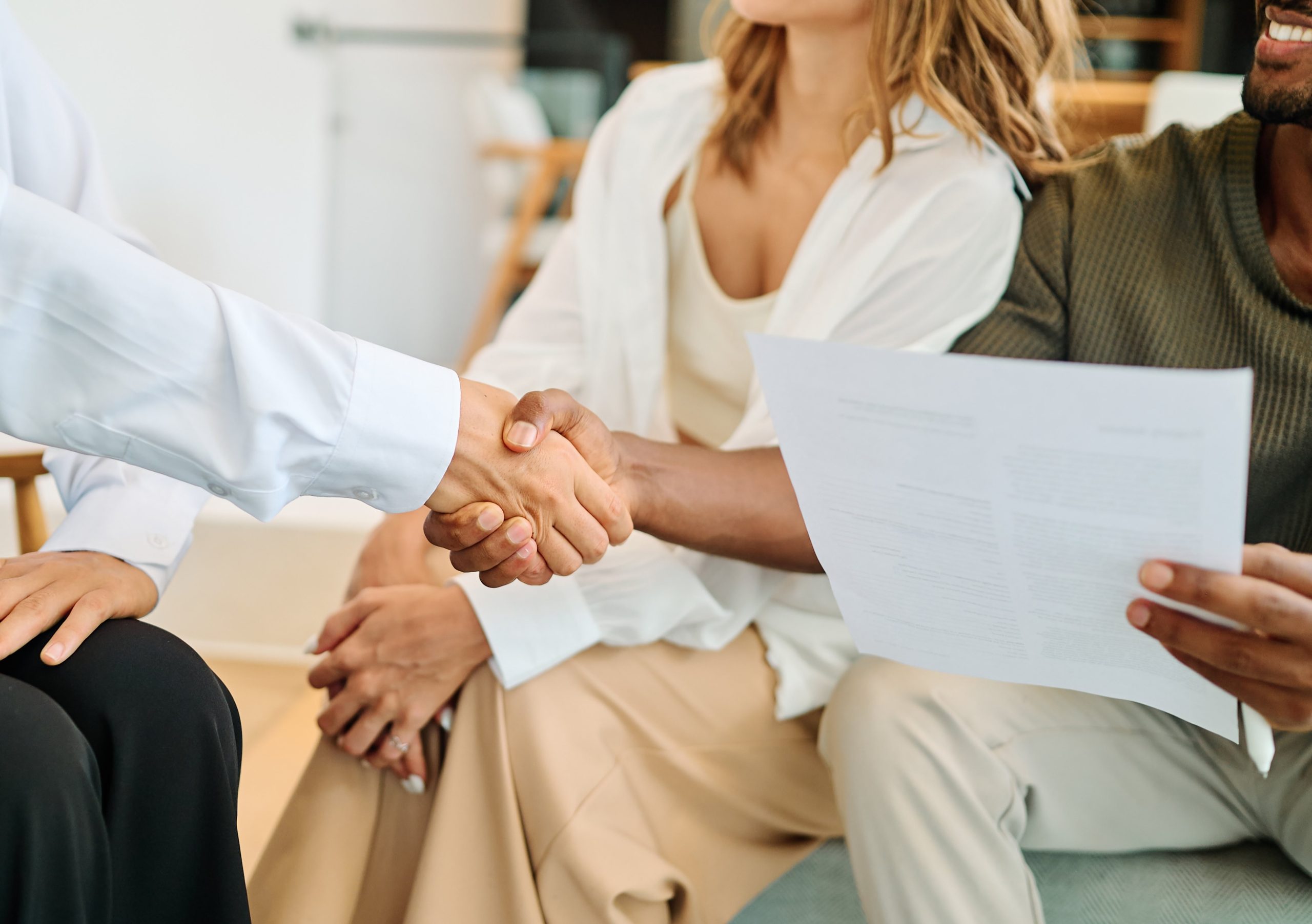 Young happy couple and an agent in a new property shaking hands or with advisor in office